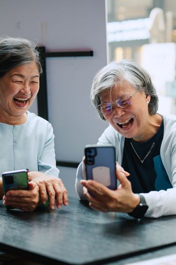 Two happy women looking at smartphone screens